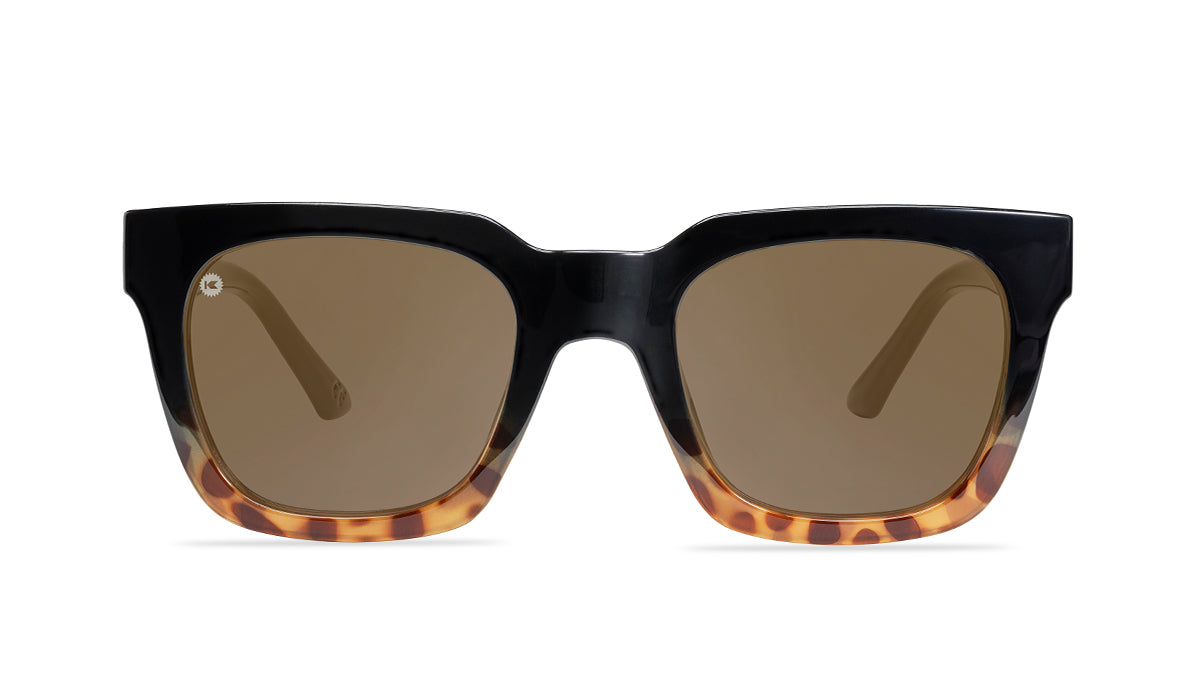 Sunglasses with a glossy black and blonde tortoise shell frame with polarized amber lenses, flyover